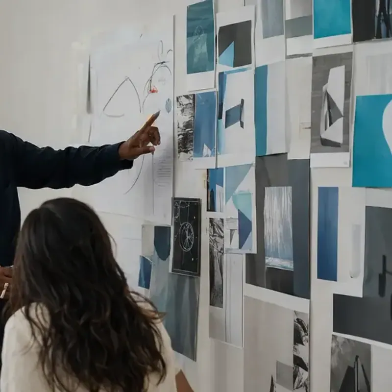 A strategist points to the moodboard wall where a brand's color and texture direction gets decided